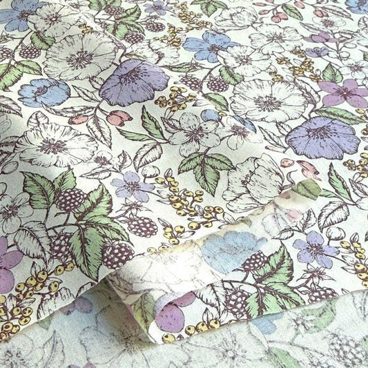 a close-up view of a fabric with a floral pattern. The pattern consists of various flowers and leaves in different colors, including white, purple, and green. The fabric appears to be a piece of paper or fabric with a printed design.