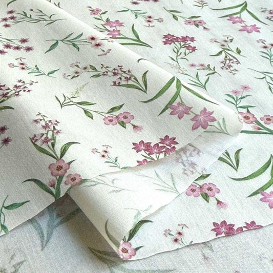 a close-up view of a fabric with a floral pattern, including pink flowers and green leaves. The fabric appears to be white, and the pattern is intricate and detailed.
