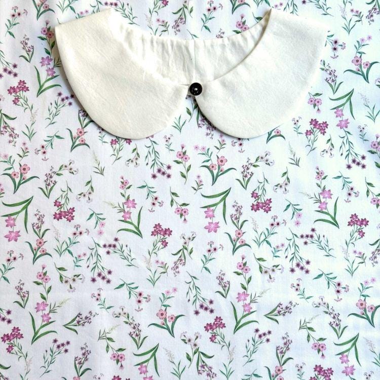 a white collar with a button, set against a background of a floral print fabric.