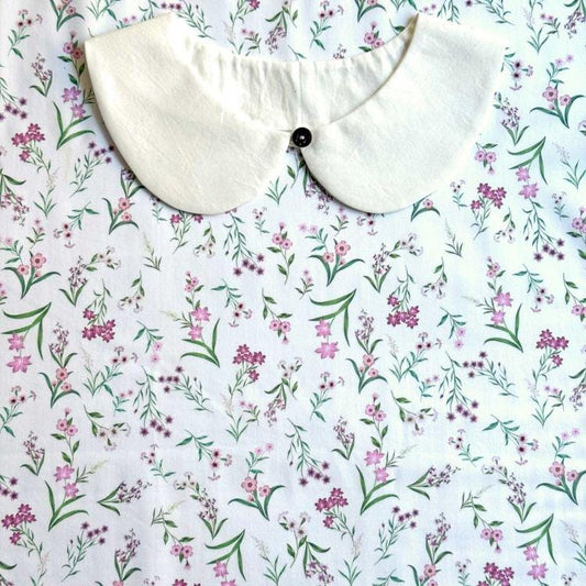 a white collar with a button, set against a background of a floral print fabric.