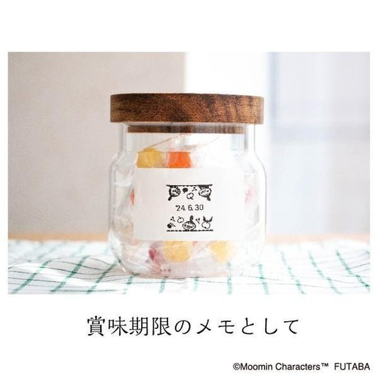 A glass jar filled with colorful candies, placed on a green and white checkered cloth.