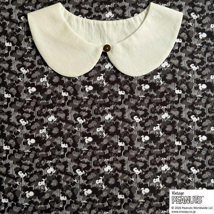 A white collar is displayed against a black and white patterned fabric with the text "Peanuts" and "Vintage Peanuts" printed on it.