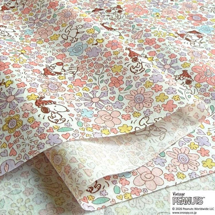 a close-up view of a fabric with a vibrant, colorful floral pattern. The pattern includes various flowers, leaves, and other decorative elements in shades of pink, yellow, and green. The fabric appears to be a type of paper or textile with a playful, whimsical design.
