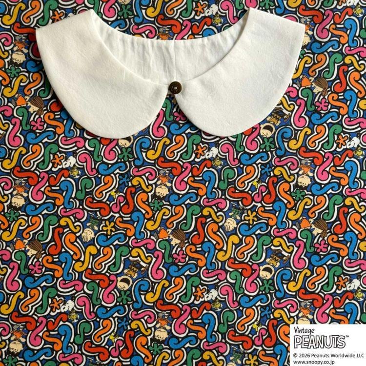 A white collar is displayed against a colorful, abstract patterned fabric.