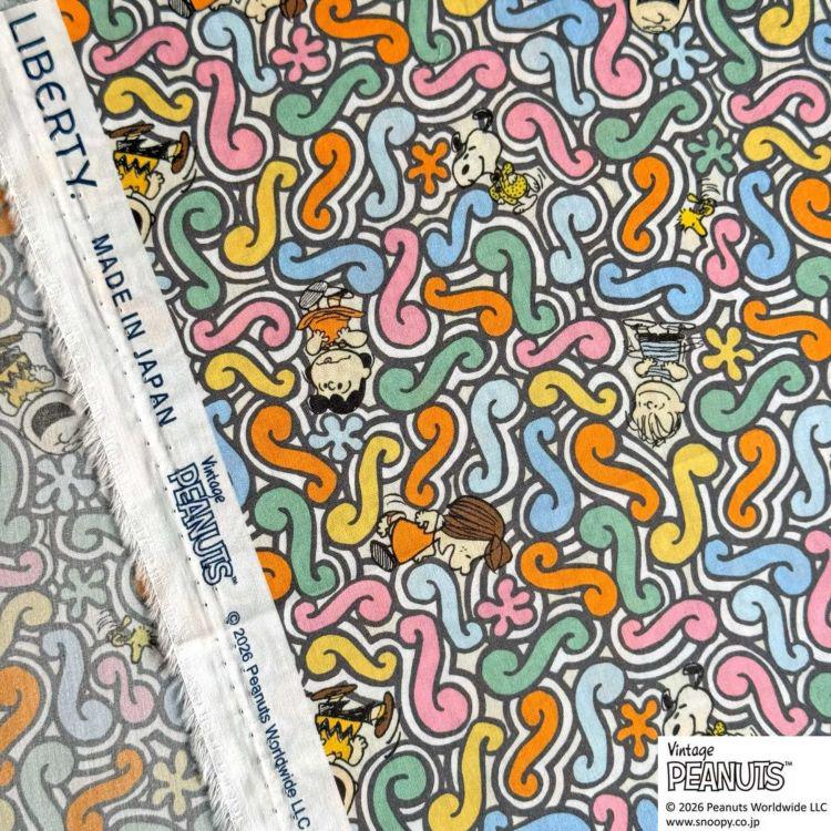 a vibrant and colorful fabric with a repeating pattern of swirls and various cartoon characters, including Peanuts.