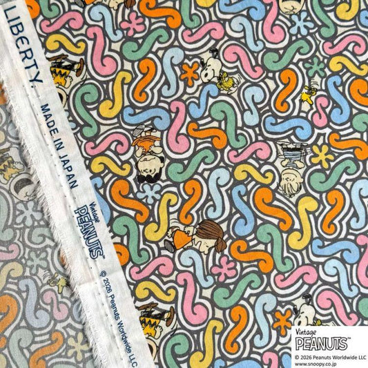 a vibrant and colorful fabric with a repeating pattern of swirls and various cartoon characters, including Peanuts.