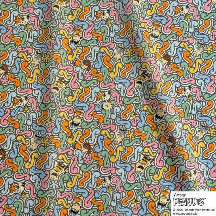 The image is a vibrant and colorful fabric with a repeating pattern of various shapes and designs, including flowers, leaves, and other organic elements. The pattern is a mix of different colors and styles, creating a visually striking and dynamic design.