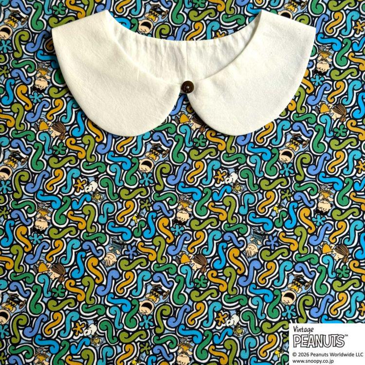 A white collar is placed on a colorful, abstract fabric with various shapes and patterns.
