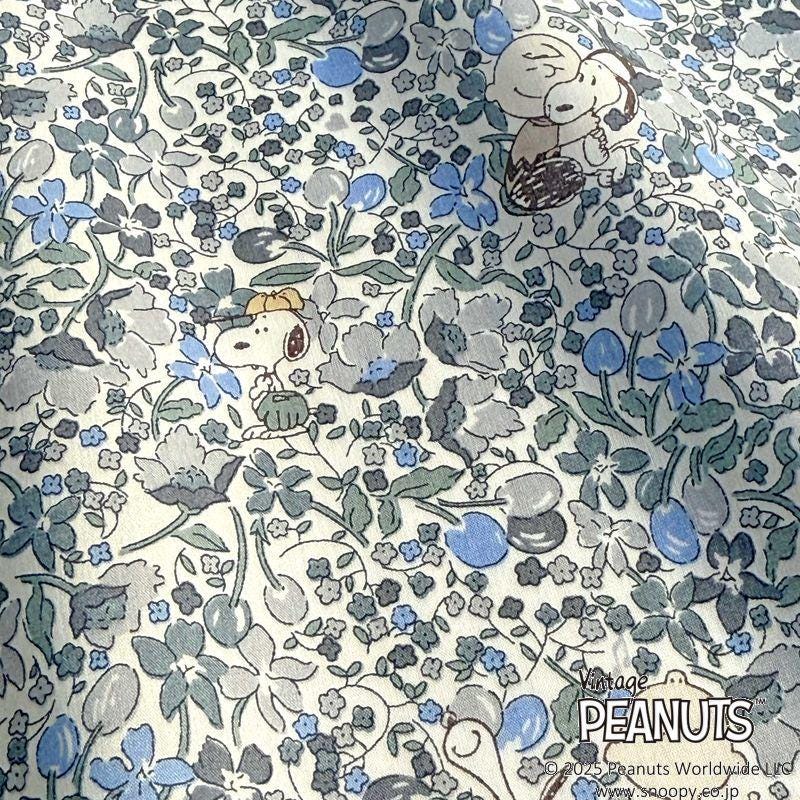 a pattern with two cartoon characters, likely from the Peanuts comic strip, surrounded by various floral and leaf-like elements in shades of blue, gray, and green.