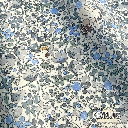 a pattern with two cartoon characters, likely from the Peanuts comic strip, surrounded by various floral and leaf-like elements in shades of blue, gray, and green.