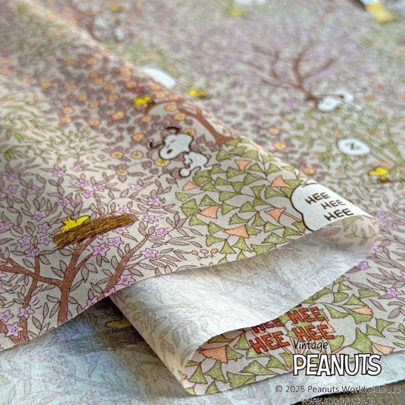 The image is a close-up of a fabric with a repeating pattern of trees, flowers, and a cartoon character resembling a dog.