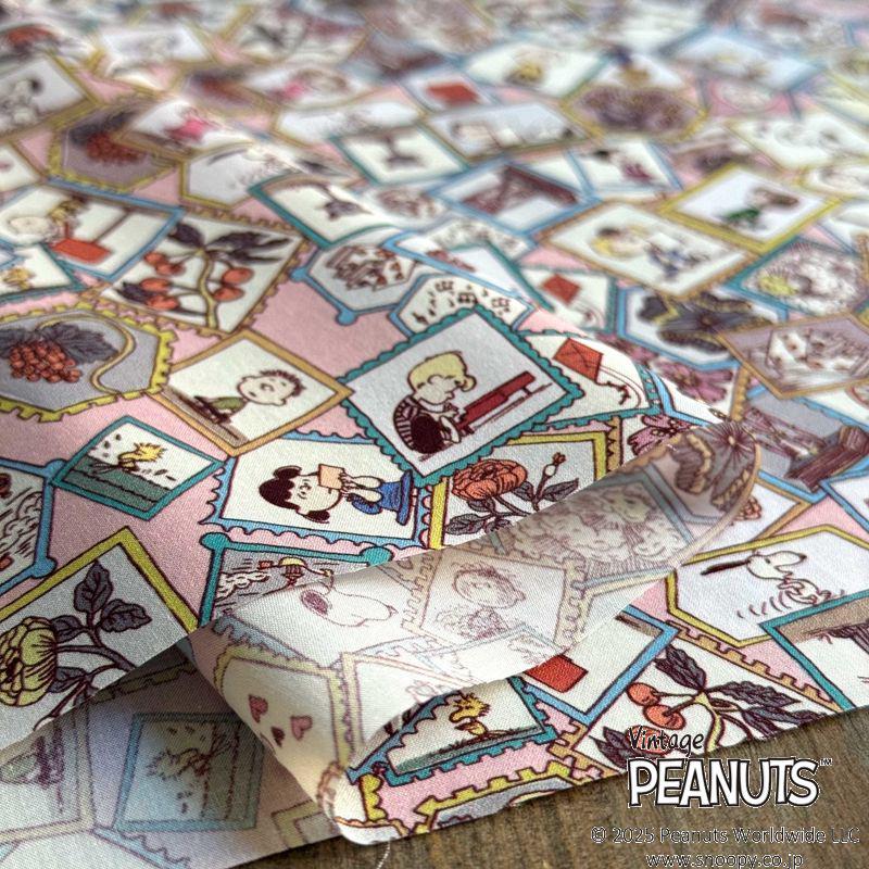 The image is a close-up of a fabric with a vibrant and colorful Peanuts-themed pattern. The pattern consists of various Peanuts characters and scenes, such as Snoopy, Charlie Brown, and other iconic figures from the Peanuts comic strip. The fabric appears to be a fabric with a repeating pattern, possibly a quilt or a textile product.