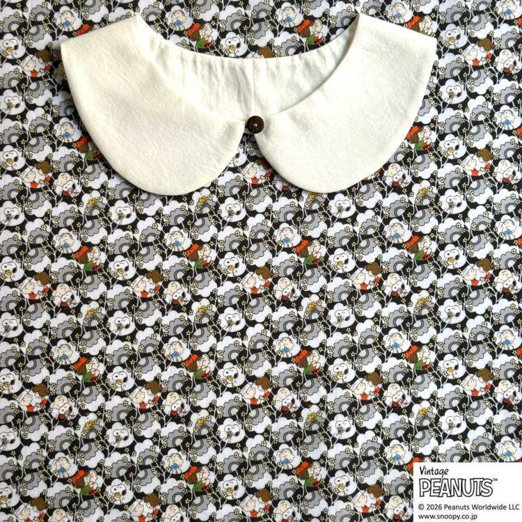 A white collar is placed on a fabric with a repeating pattern of cartoon faces in various colors.