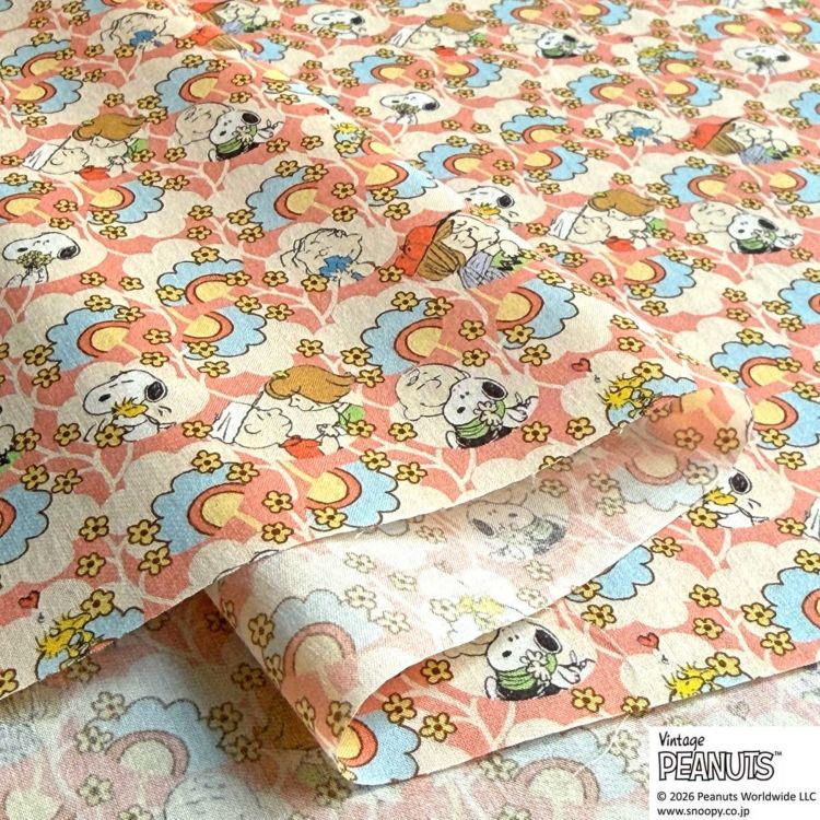 a close-up view of a fabric with a repeating pattern of cartoon characters, including Snoopy, Peanuts, and other iconic characters from the Peanuts comic strip.