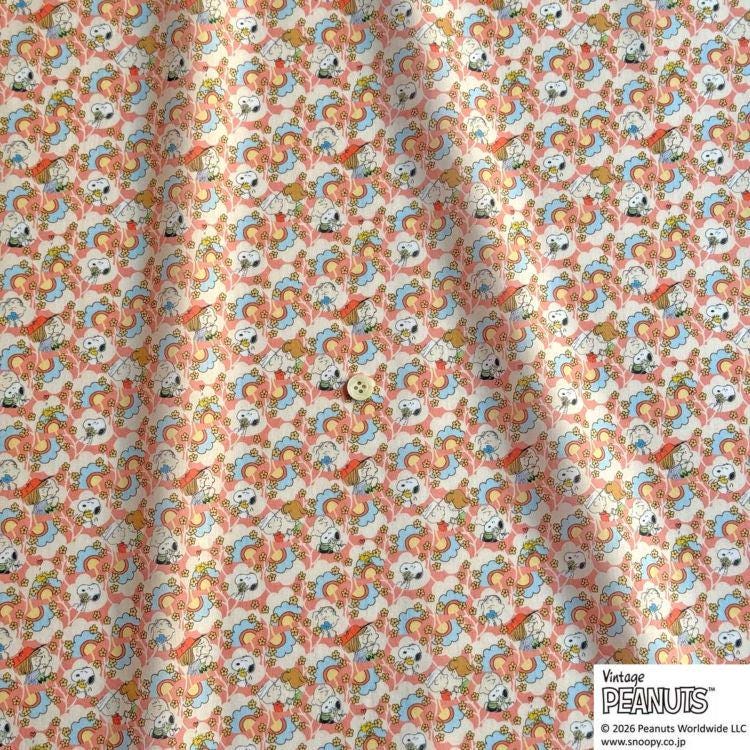 a fabric with a repeating pattern of cartoon characters, specifically the Peanuts characters, in various colors such as orange, blue, and white. The pattern is intricate and detailed, creating a visually appealing design.