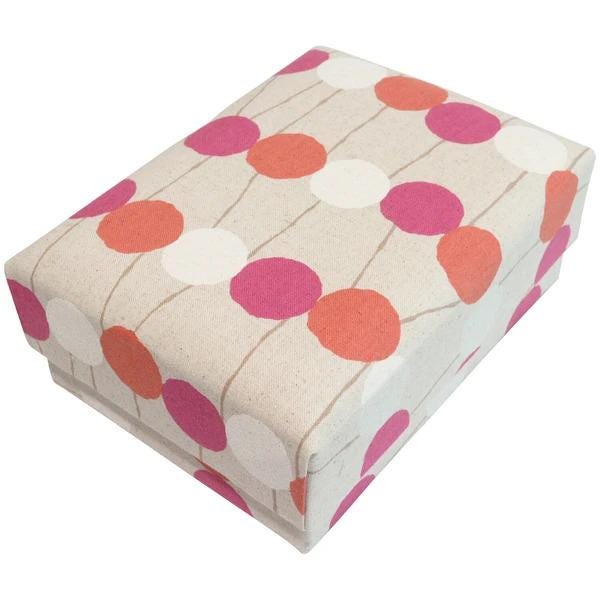 a rectangular box with a pattern of pink and orange circles on a beige background.