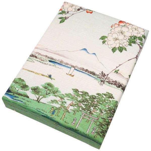 The image is a rectangular box with a printed design depicting a serene landscape with mountains, trees, and a river.