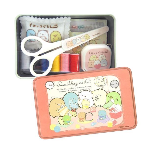 A pink tin box containing a sewing kit with a pair of scissors, a sewing kit, and various other sewing tools. The tin box also has a label that reads "SukiyoGurahi" and features a colorful illustration of cartoon characters.