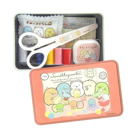 A pink tin box containing a sewing kit with a pair of scissors, a sewing kit, and various other sewing tools. The tin box also has a label that reads "SukiyoGurahi" and features a colorful illustration of cartoon characters.