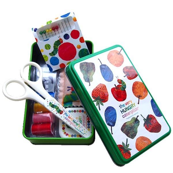A green tin box with a pattern of colorful fruits and vegetables, including strawberries, apples, and oranges, along with a pair of scissors.