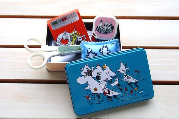 a blue tin with a cartoon illustration of a group of characters, including a moose, a cat, and a bird, along with a pair of scissors and a small red book.