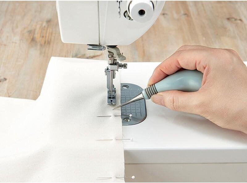 A hand is using a sewing machine to stitch two pieces of fabric together.