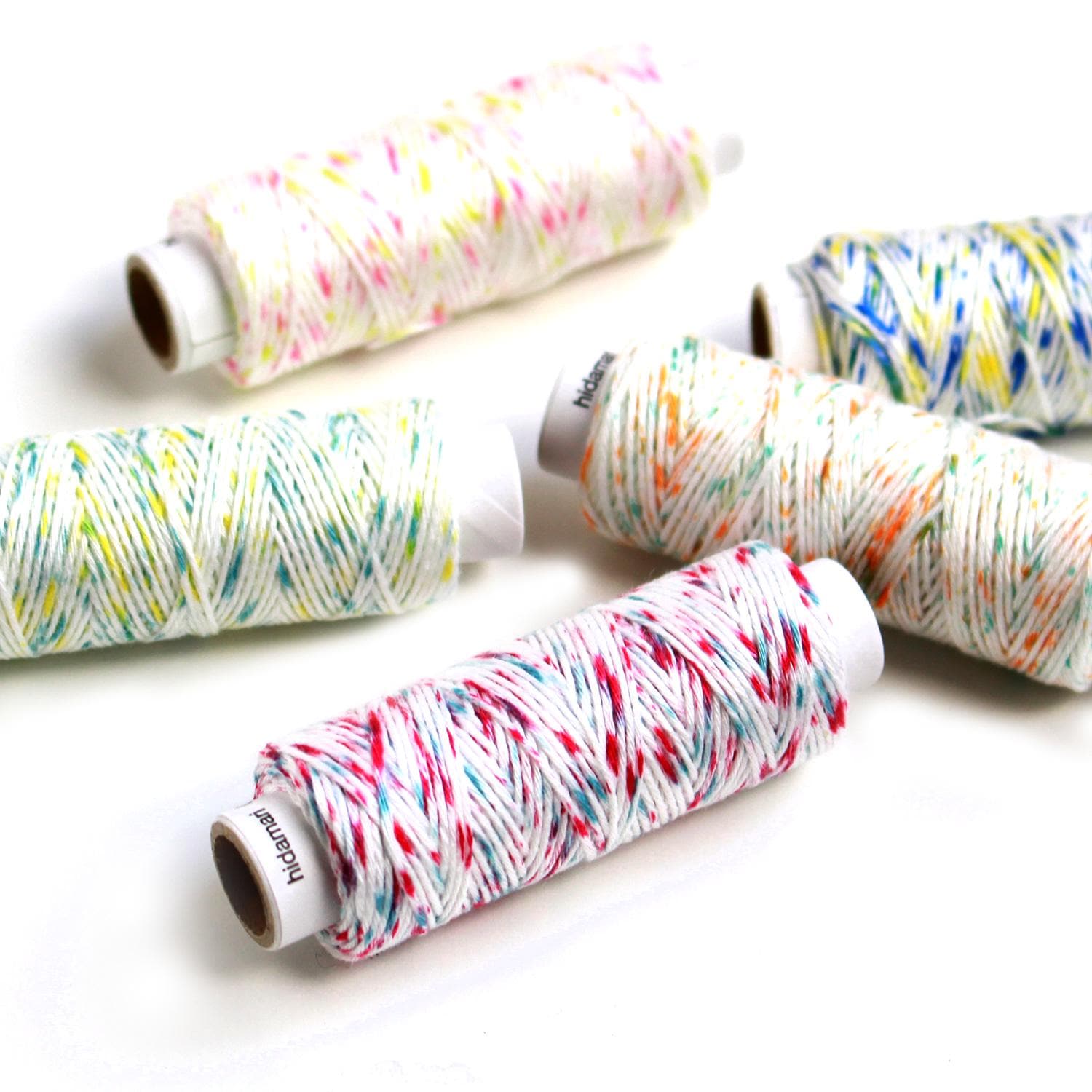a collection of colorful spools of thread or yarn, each with a different pattern and color, arranged on a white background.