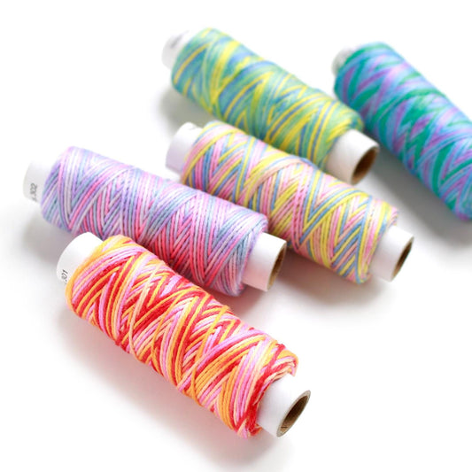 a collection of colorful spools of thread arranged on a white background.