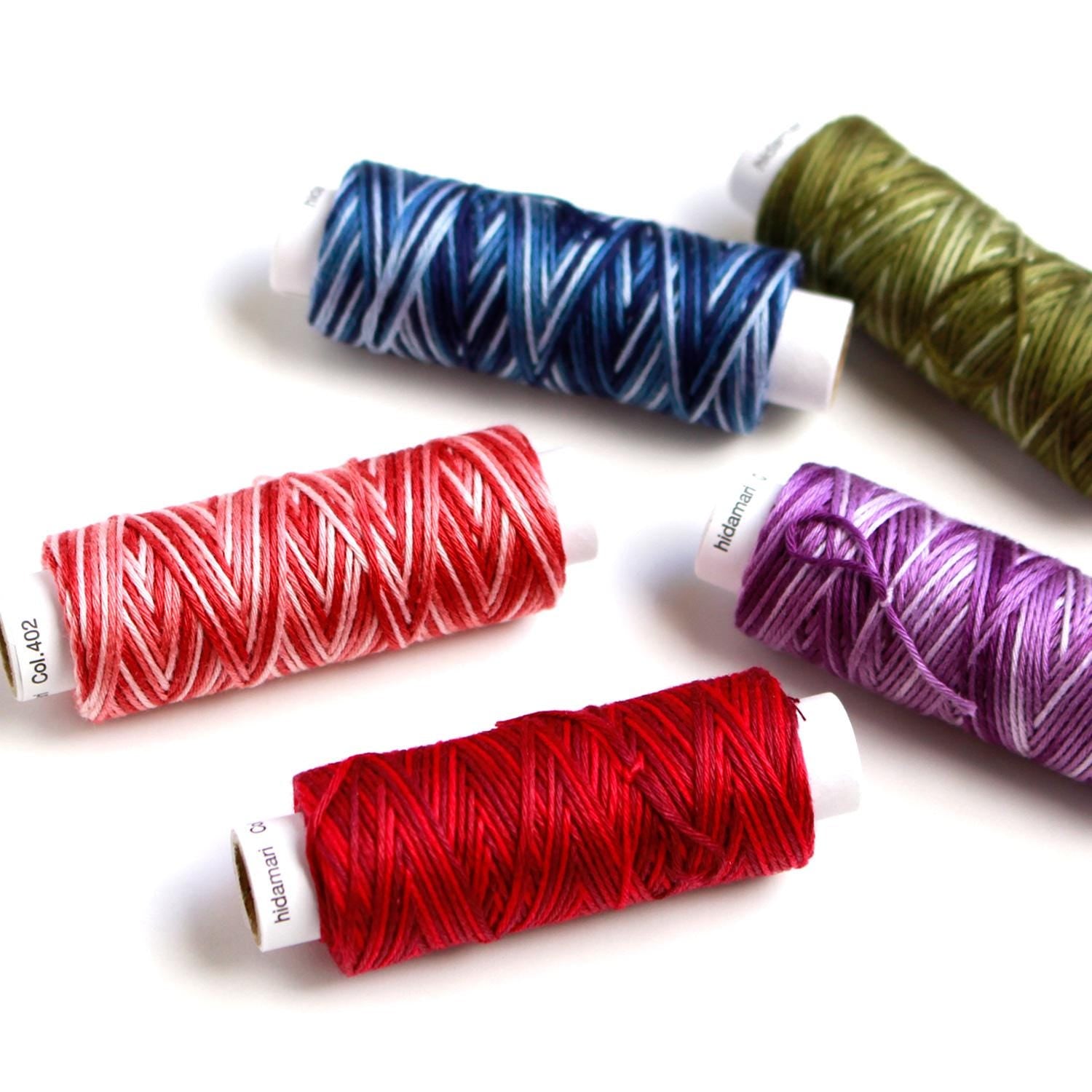 five spools of thread in various colors, including red, blue, green, purple, and pink, arranged on a white background.