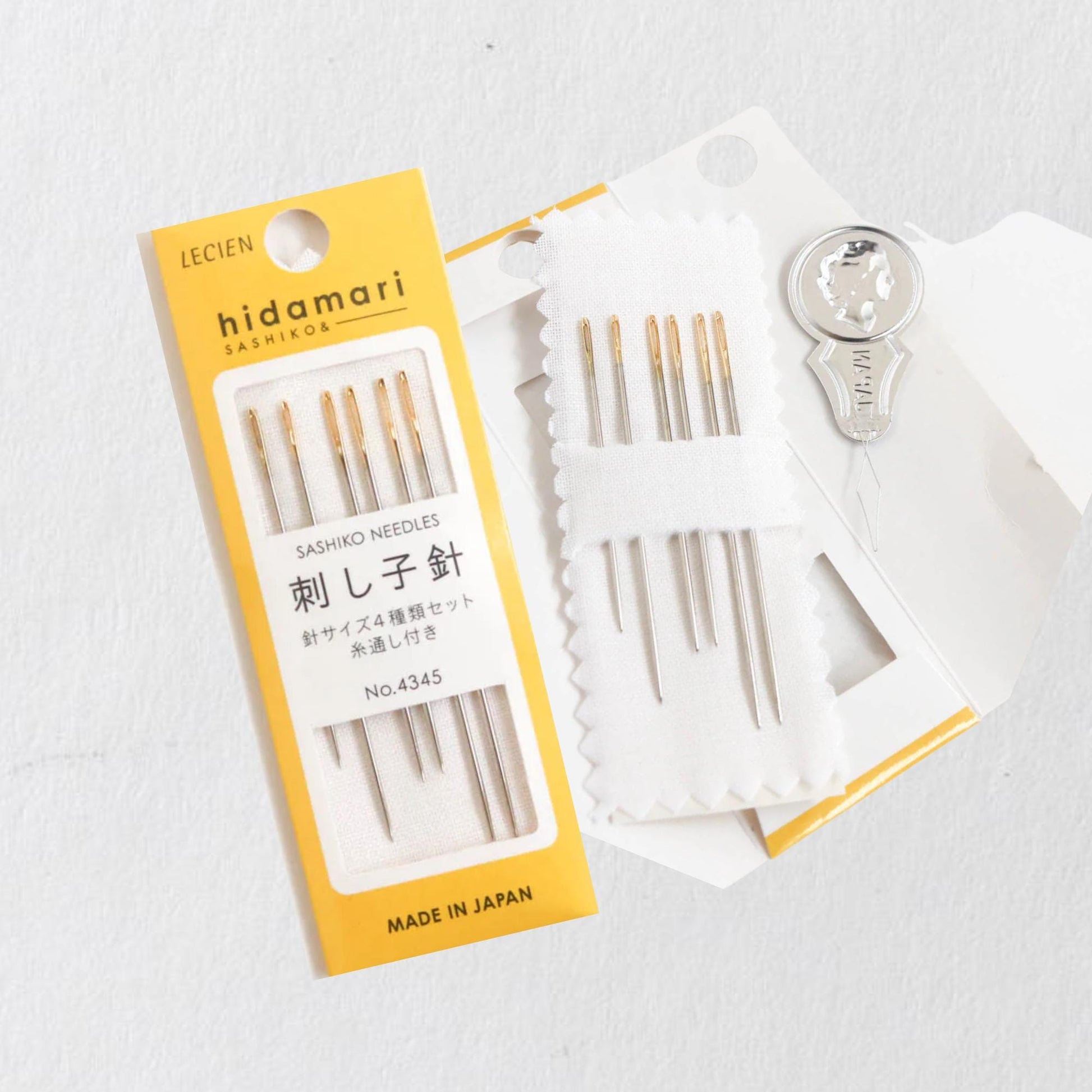 A yellow box containing a set of sewing needles and a keychain, with the text "LECIEN HIDAMARI SASHISHI OSAISHI" printed on it.