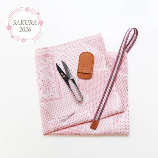 a pink and white patterned cloth, a pair of scissors, a leather pouch, and a zipper pouch, all arranged on a white background.