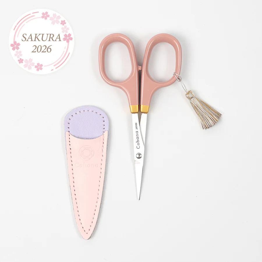 a pair of pink scissors and a pink leather scissor holder with a tassel on a white background.