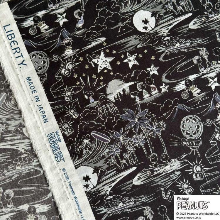 The image is a close-up of a fabric with a black and white pattern featuring various cartoon-like characters and objects, such as stars, clouds, and palm trees. The fabric appears to be a piece of clothing or textile with a unique design.