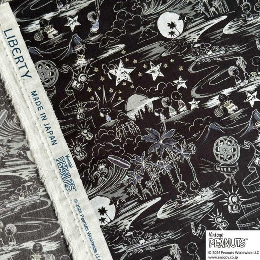 The image is a close-up of a fabric with a black and white pattern featuring various cartoon-like characters and objects, such as stars, clouds, and palm trees. The fabric appears to be a piece of clothing or textile with a unique design.