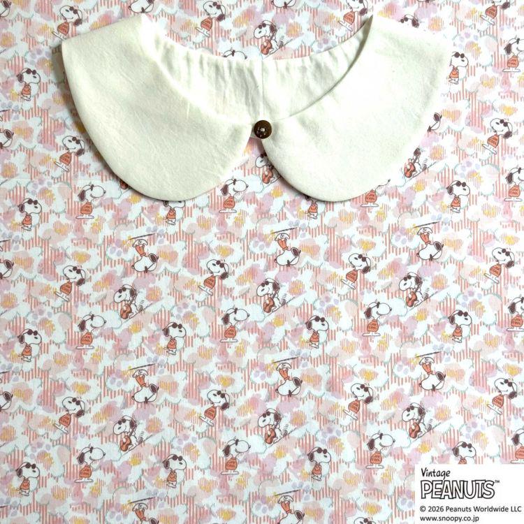 A white collar is placed on a pink and white floral background with the text "Peanuts" visible.