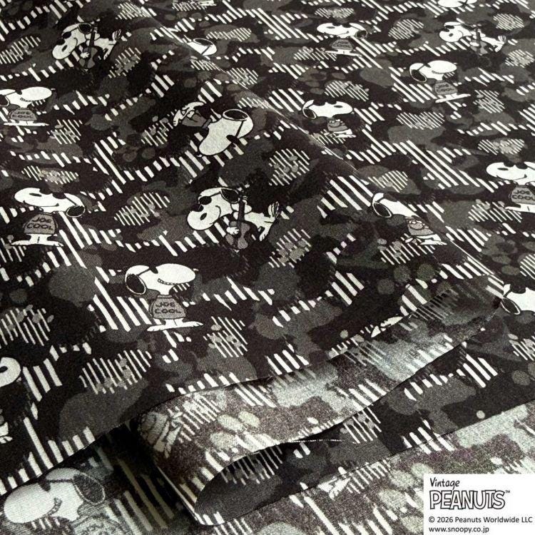 a close-up view of a fabric with a repeating pattern of black and white silhouettes of cartoon characters, resembling the iconic Peanuts characters.