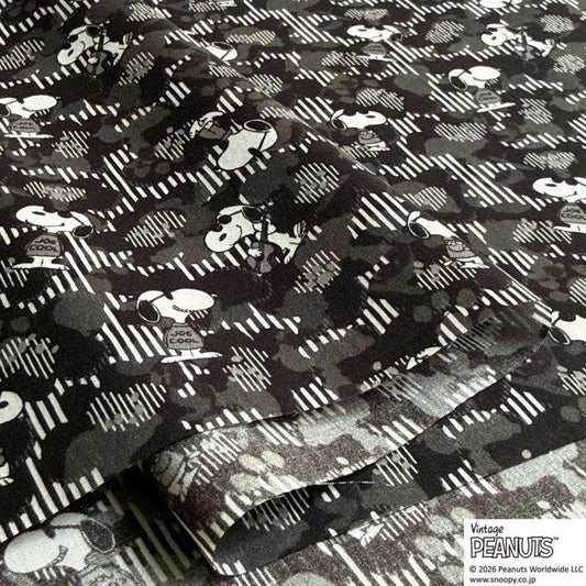 a close-up view of a fabric with a repeating pattern of black and white silhouettes of cartoon characters, resembling the iconic Peanuts characters.