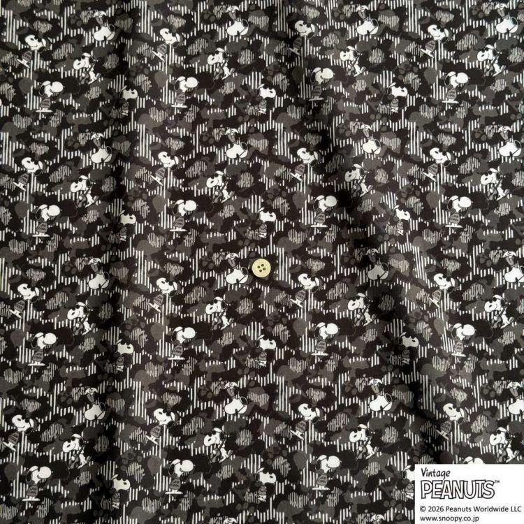 The image is a close-up of a fabric with a repeating pattern of black and white silhouettes of cartoon characters, resembling the iconic Peanuts characters.