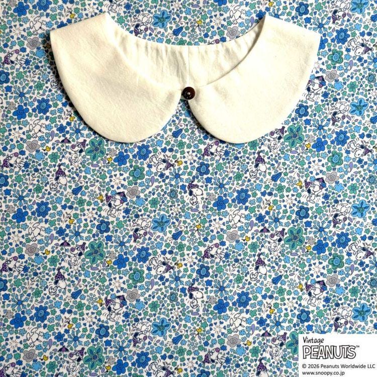 A white collar is placed on a fabric with a blue and white floral pattern.