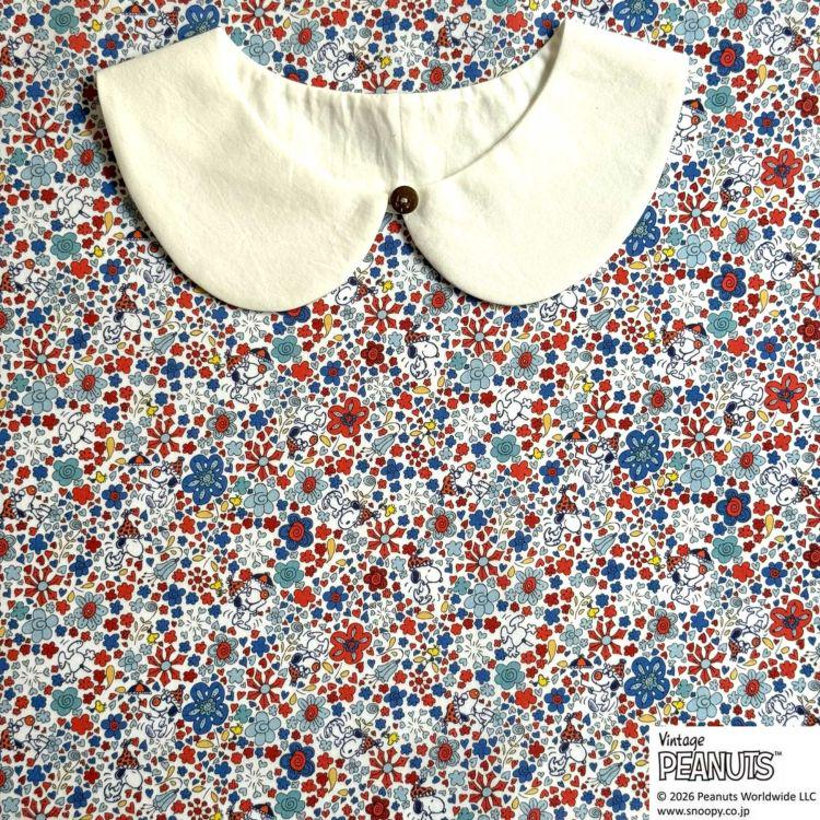 A white collar is displayed on a colorful floral fabric background.