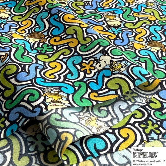 The image is a vibrant and colorful fabric with a repeating pattern of swirls, flowers, and cartoon characters, including Snoopy, the beloved Peanuts character.