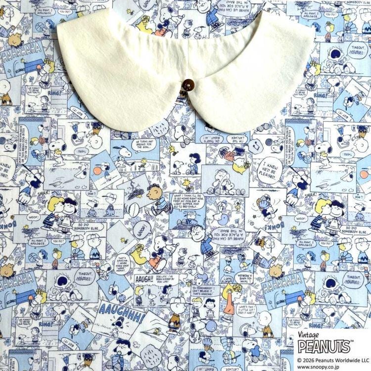 The image is a collage of various Peanuts comic strip panels, featuring characters such as Snoopy, Charlie Brown, and Peanuts. The collage is spread across a fabric surface, with a white collar placed on top of it.