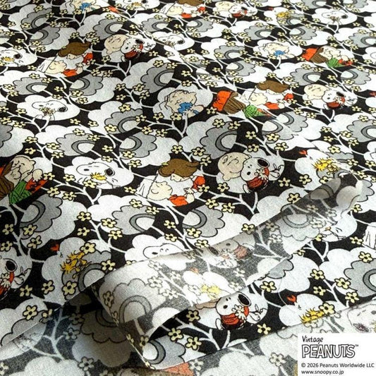 a close-up view of a fabric with a repeating pattern of cartoon characters, including Snoopy, the beloved Peanuts character. The pattern is a mix of black, white, and gray colors, with various shades of gray and white creating a visually striking design. The characters are depicted in different poses and expressions, adding a dynamic and playful element to the fabric.