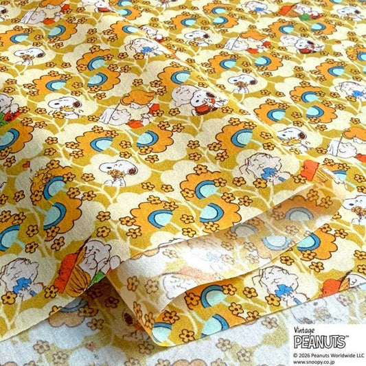 a fabric with a repeating pattern of cartoon characters, specifically the Peanuts characters, in shades of yellow, orange, and blue.