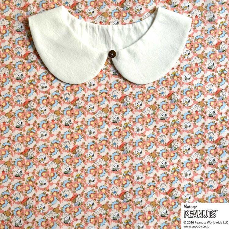 A white collar is displayed on a patterned fabric with a repeating design of cartoon characters.