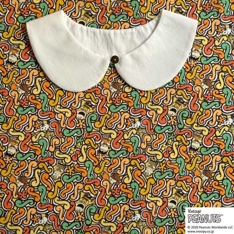 A white collar is displayed against a colorful, abstract patterned fabric.