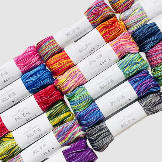a collection of colorful yarn skeins arranged in rows, with each skein having a label that includes Japanese text.
