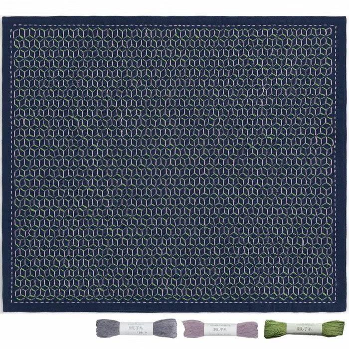 a square-shaped fabric with a repeating geometric pattern in shades of blue and green. The fabric appears to be a handmade textile, possibly a quilt or a decorative piece. The image also includes three spools of thread, likely for sewing or embroidery purposes, and a label indicating the thread colors.