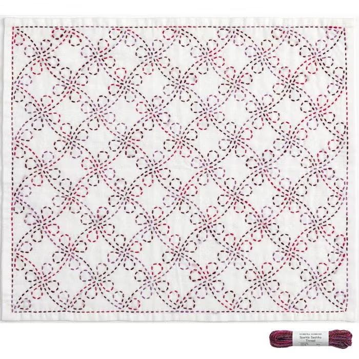 a square-shaped fabric with a repeating pattern of red and white flowers or flowers with red and white petals.