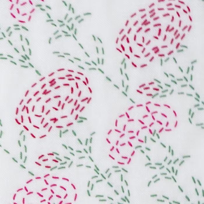 a close-up view of a white fabric with a floral pattern created using red and green embroidery stitches.